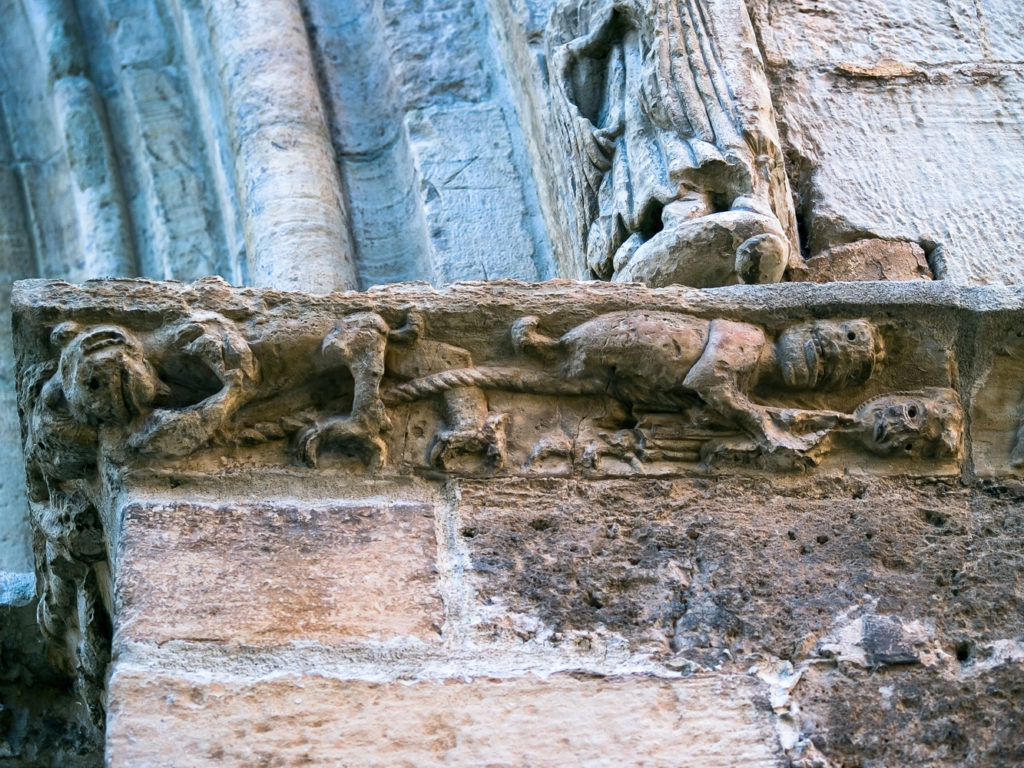 Varios demonios atan con cuerdas a los pecadores en el cimacio de la portada de la iglesia de San Salvador en Cifuentes Guadalajara