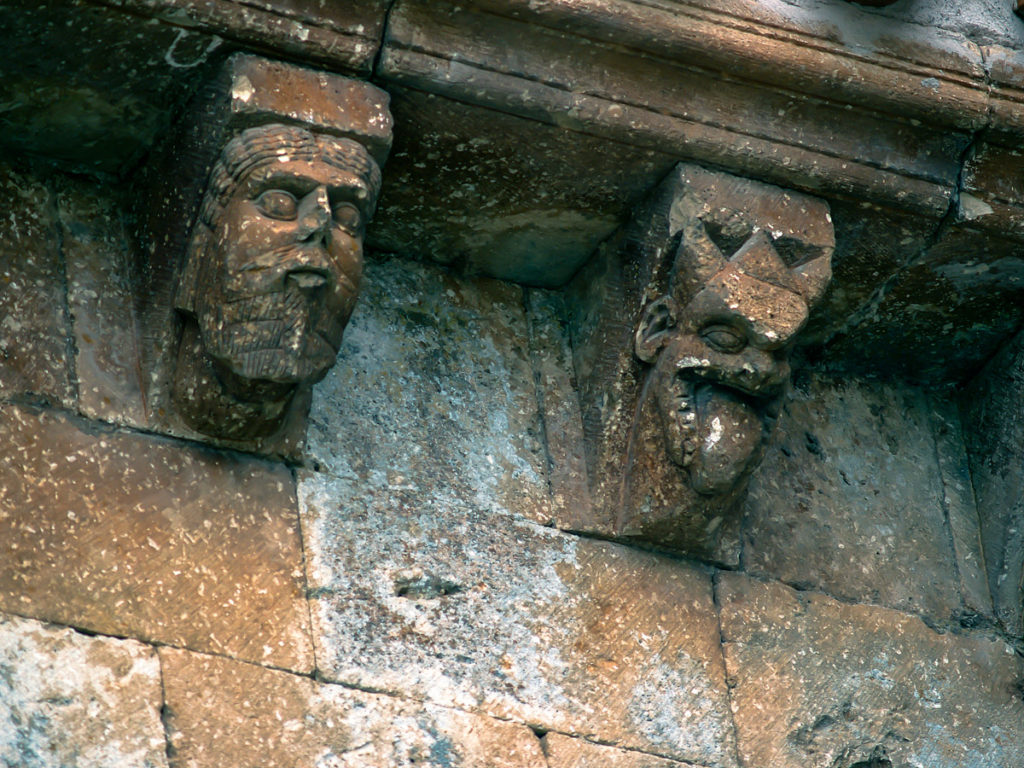 Iglesia de San Miguel en la localidad burgalesa de Arlanzon Dos de los canecillos del alero de la fachada sur La cabeza de la derecha sugiere la figura de un demonio justo lo contrario que la de la izquierda